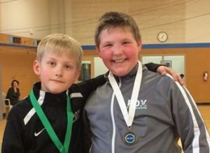 Two boys smiling with sports medals.