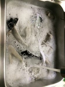 Clothes soaking in soapy water in sink.