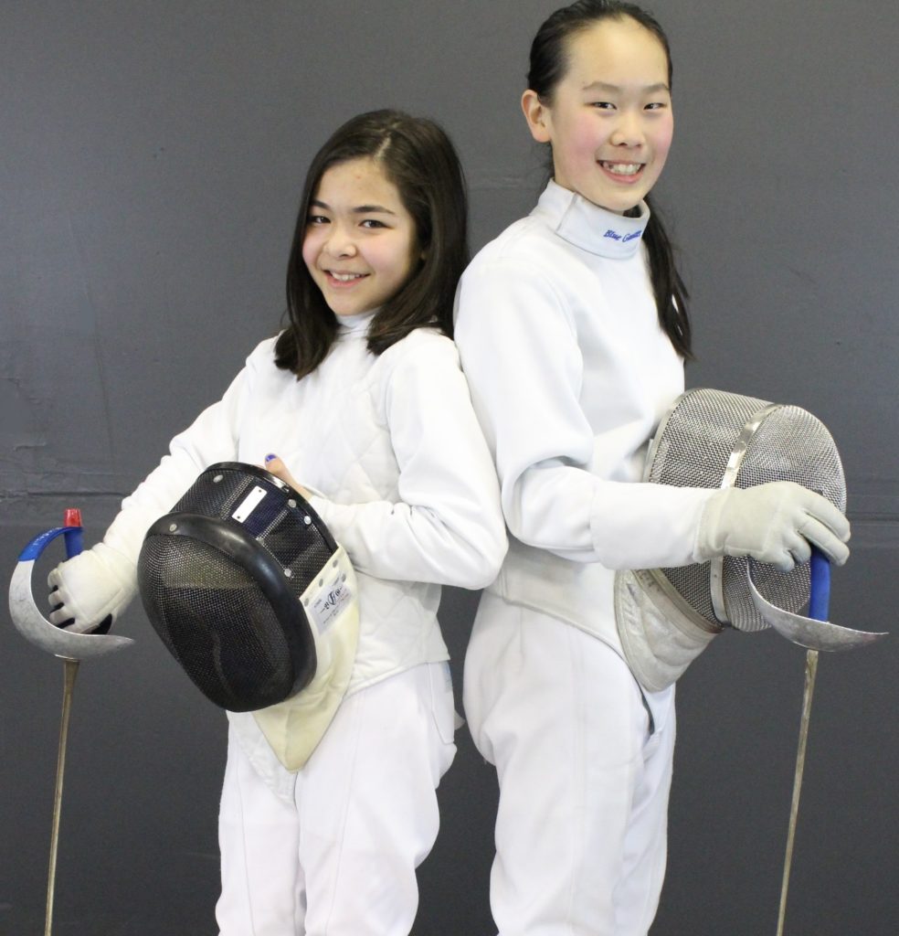 Two young fencers posing with masks.
